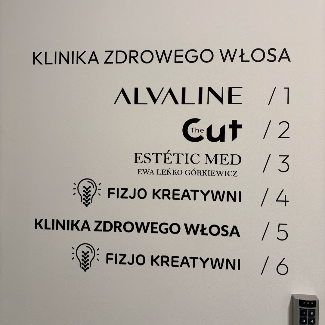 Tablica informacyjna na ścianie korytarza: ESTÉTIC MED Gabinet 3